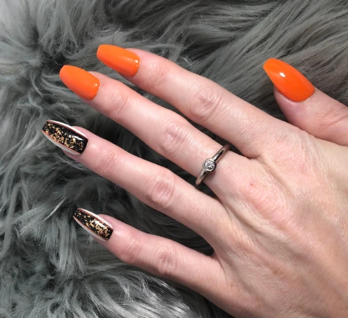 Short orange and black nails with gold pattern design